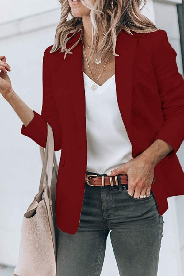 Vrouw in rode blazer met witte top en grijze broek, draagt beige handtas. Modieuze dameskleding, casual chic stijl, herfstmode.