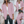 Vrouw in roze blazer, witte blouse en zwarte broek met bruine riem, draagt beige handtas. Mode, dameskleding, stijlvolle outfit.