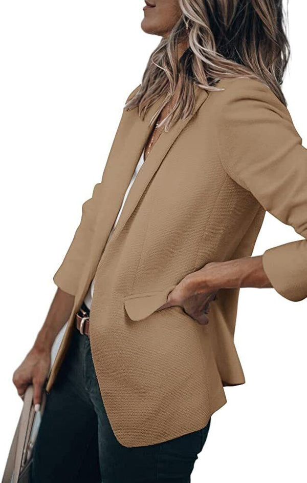 Vrouw in stijlvolle beige blazer, witte top en zwarte broek, houdt een tas vast. Mode, dameskleding, zakelijke outfit, trendy blazer.