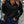 Vrouw in zwarte geribbelde trui met rits, blauwe jeans en zwarte gewatteerde schoudertas. Modieuze herfstoutfit, casual straatstijl.