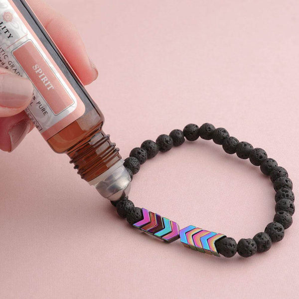 Zwarte lavasteen armband met olie diffuser, kleurrijke pijlvormige kralen, essentiële olie applicatie, aromatherapie sieraden, wellness accessoire.