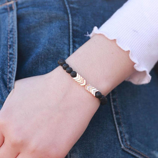 Pols met lavasteen armband en metalen pijlen, olie diffuser sieraad, modieuze accessoire, aromatherapie, casual stijl, denim achtergrond.