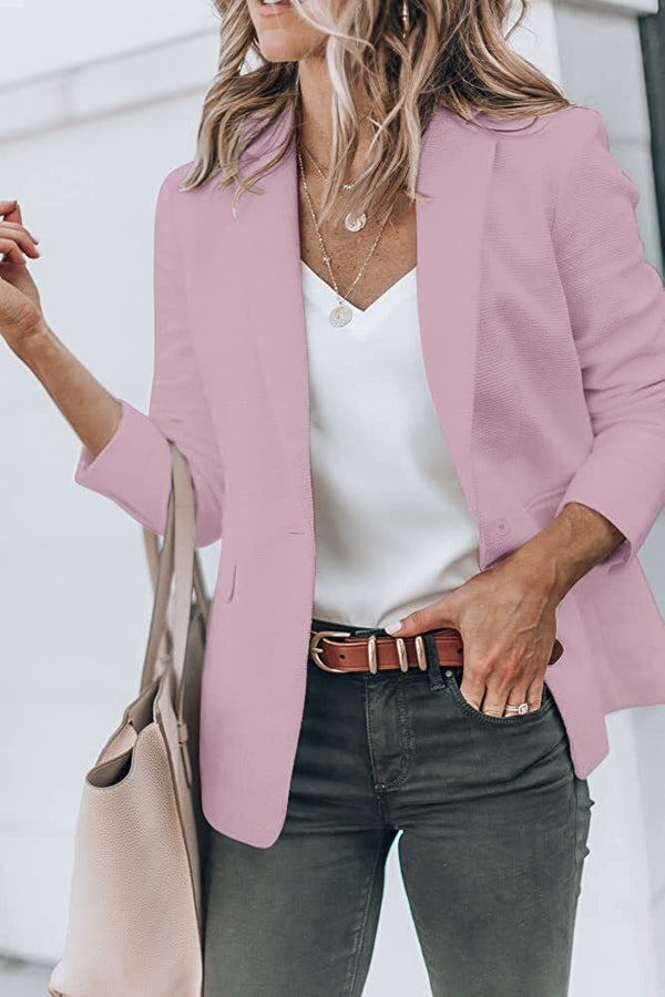 Vrouw in roze blazer met witte top en groene broek, draagt beige tas. Modieuze dameskleding, casual chic stijl, trendy outfit.