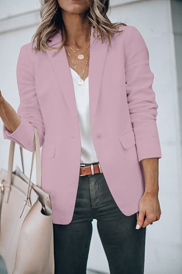 Vrouw in roze blazer met witte blouse en zwarte broek, draagt een beige handtas. Stijlvolle zakelijke outfit, mode voorjaarscollectie.