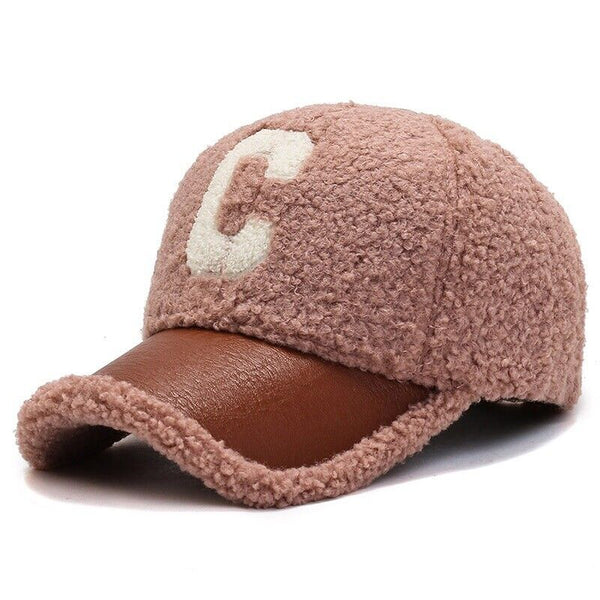 Roze teddy cap met bruine leren klep en witte letter "C". Modieuze winteraccessoire, warme en stijlvolle pet voor dames en heren.