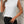Vrouw in witte mouwloze top en zwarte broek drinkt koffie; stijlvolle casual outfit, mode, dameskleding, trendy look, stedelijke achtergrond.
