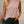 Vrouw in roze mouwloze top met diagonale plooien, zwarte broek en zwarte schoudertas. Modieuze dameskleding, casual chique stijl.