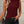 Vrouw in stijlvolle bordeauxrode mouwloze top met zwarte broek en schoudertas, modieuze outfit, casual chique look, trendy dameskleding.