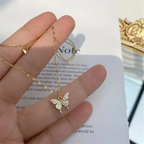 Gouden vlinderketting met kristallen hanger op een hand, elegante sieraden, modieuze accessoires, perfect cadeau voor vrouwen, luxe uitstraling.