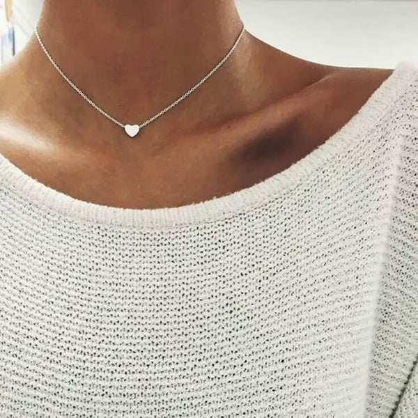 Witte trui met zilveren hartvormige ketting, minimalistisch design, damesmode, elegante sieraden, trendy accessoires, casual stijl.