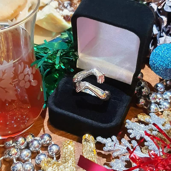 Zilveren ring in zwart fluwelen doosje, omringd door kerstdecoraties en glinsterende ornamenten. Perfect cadeau-idee voor de feestdagen.