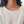 Vrouw met zilveren hartvormige ketting, gebreide trui, minimalistische sieraden, modieuze accessoires, elegante damesstijl, casual outfit.