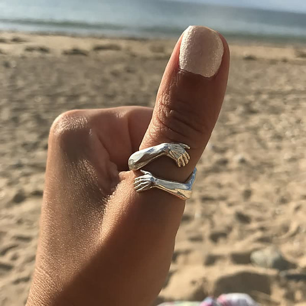 Zilveren ring met armen ontwerp om duim, strandachtergrond, unieke sieraden, handgemaakt, modieuze accessoire, zomerse stijl.