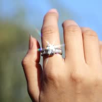 Hand met glinsterende diamanten ring tegen blauwe hemel, close-up. Luxe sieraden, verlovingsring, sprankelend juweel, elegante stijl.