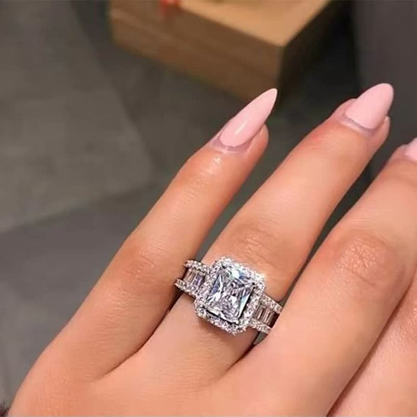 Luxe diamanten verlovingsring met vierkante steen en baguette zijstenen op hand, elegant design, perfect voor huwelijksaanzoek.
