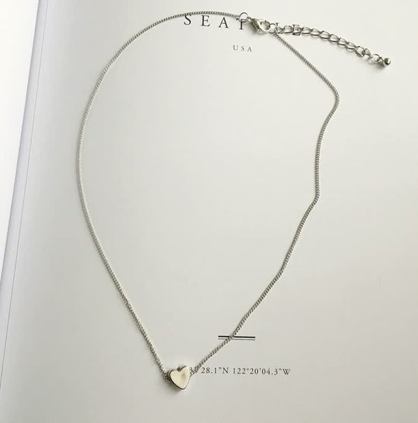 Zilveren ketting met hartvormige hanger op witte achtergrond, minimalistisch ontwerp, perfect voor dames, sieraden, cadeau-idee, elegant accessoire.