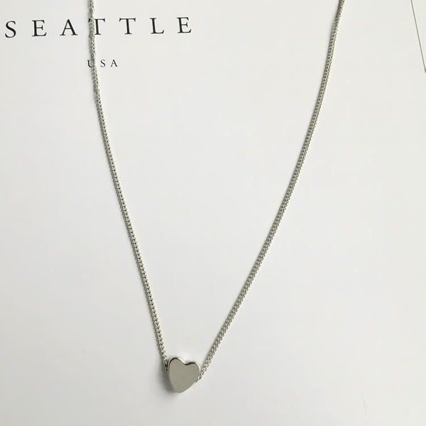 Zilveren ketting met hartvormige hanger op witte achtergrond, minimalistisch design, perfect voor cadeau, sieraden uit Seattle, USA.
