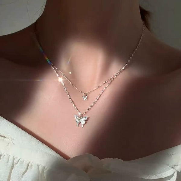 Twee delicate vlinderkettingen op een vrouwelijke hals, glinsterend in zonlicht. Perfecte sieraden voor elegante en modieuze dames.
