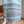 Hand houdt denim broekspijp met kleurrijk etnisch patroon vast, inclusief geometrische vormen en tribal motieven. Perfect voor boho mode en casual stijl.