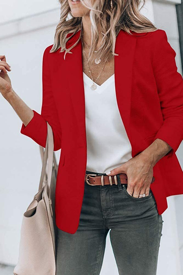 Vrouw in rode blazer met witte top en grijze broek, draagt beige tas. Modieuze dameskleding, zakelijke casual outfit.