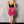 Vrouw in zwarte top en roze paillettenrok met veren, staand tegen grijze muur. Modieuze outfit, trendy kleding, avondkleding, feestelijke look.