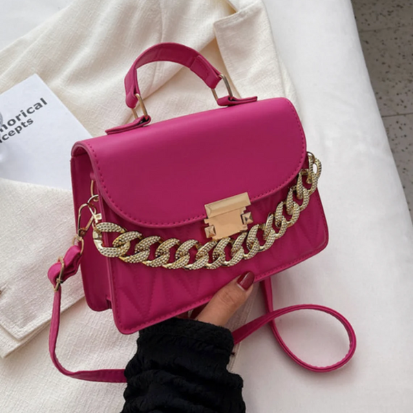Felroze handtas met gouden ketting, verstelbare schouderriem en handvat, op witte achtergrond. Trendy damesaccessoire, modieuze tas.