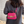 Vrouw met roze handtas met gouden ketting, gedragen over schouder. Stijlvolle modeaccessoire, perfect voor trendy outfits en dagelijkse elegantie.