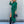 Vrouw in groene midi-jurk met knoopsluiting, zwarte laarzen en handtas. Modieuze dameskleding, herfststijl, elegante outfit.