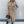 Vrouw in beige overhemdjurk met ceintuur, zwarte laarzen en handtas. Stijlvolle mode, herfstoutfit, elegante dameskleding.