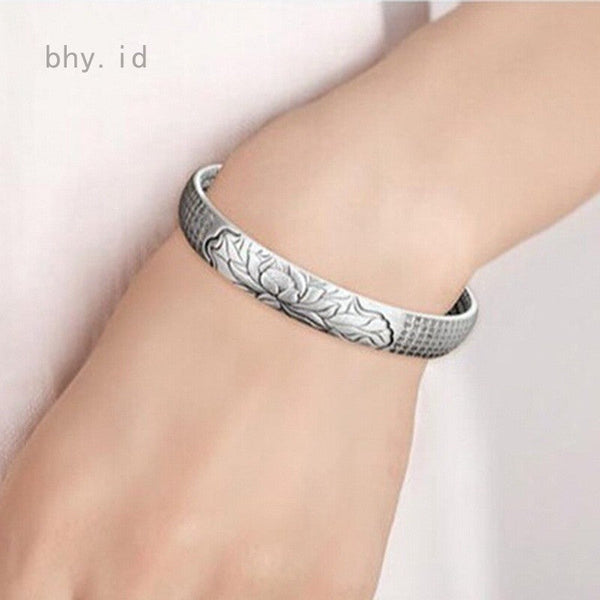 Zilveren armband met lotusgravure op pols, elegant en stijlvol design, perfect voor damesmode en sieradencollecties.