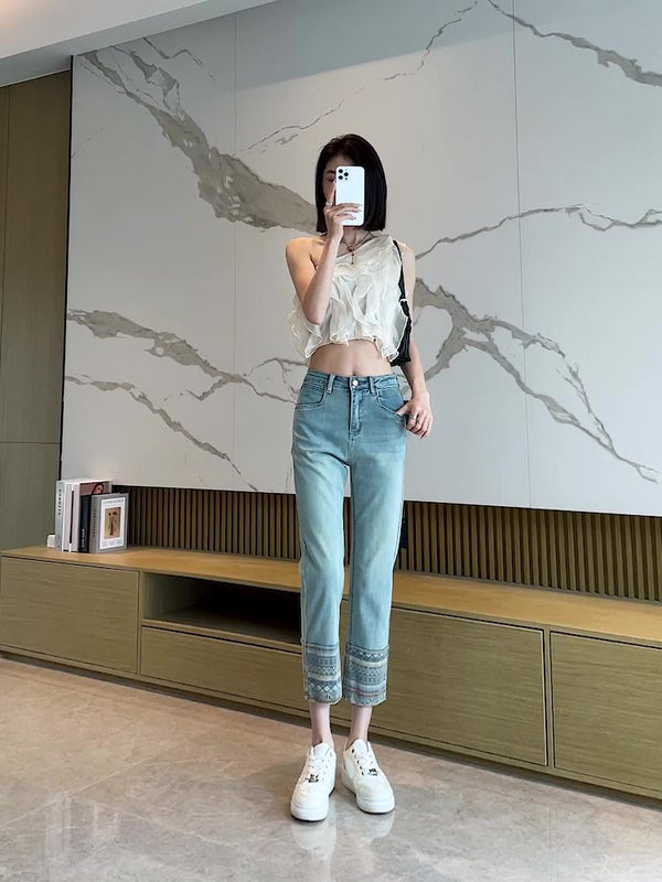 Vrouw in moderne woonkamer, draagt casual jeans en witte top, maakt selfie met smartphone. Stijlvolle interieurdecoratie, marmeren muur.