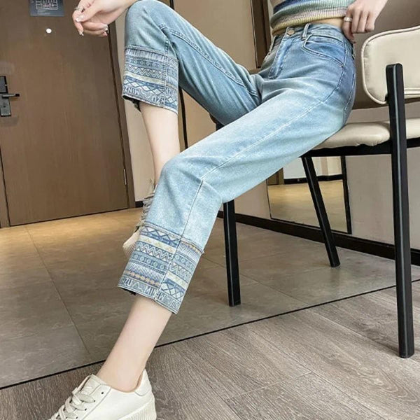 Vrouw draagt lichtblauwe jeans met etnische print op de zoom, gecombineerd met witte sneakers. Modieuze casual outfit voor dames.