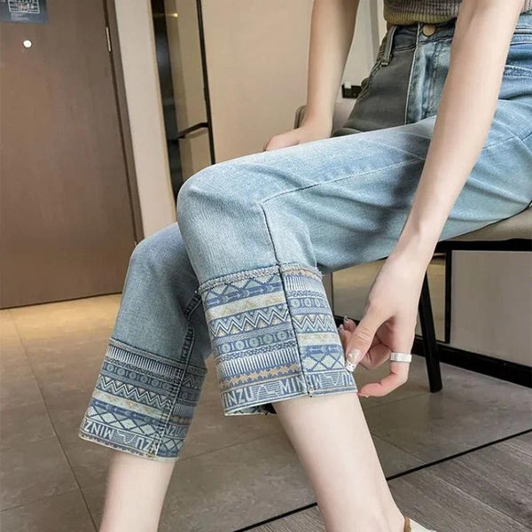 Vrouw met lichtblauwe jeans met etnische print op omgeslagen zoom, zittend op stoel. Trendy damesmode, casual outfit, denim stijl.