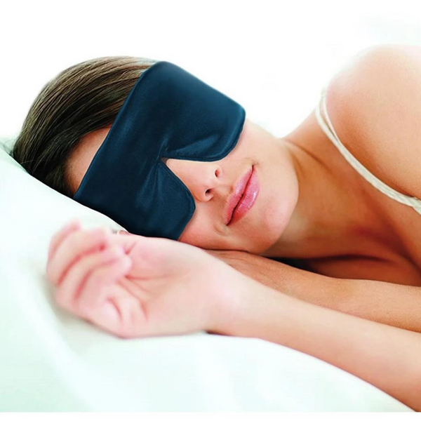 Vrouw slaapt met zwarte zijden slaapmasker, liggend op wit kussen. Comfortabel slapen, slaapaccessoires, rustgevende nachtrust.