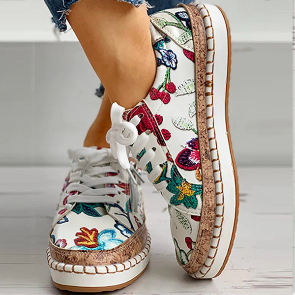 Witte damessneakers met kleurrijke bloemenprint, kurken zool en witte veters. Comfortabele slip-on schoenen, perfect voor casual lente- en zomermode.