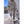 Vrouw in beige sportoutfit met hoodie en legging, draagt witte sneakers en een kleine witte handtas, buiten op zonnige dag.