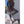 Vrouw in grijze sportieve outfit met legging en oversized vest, witte sneakers en handtas, poseert tegen een muur. Casual mode, dameskleding.