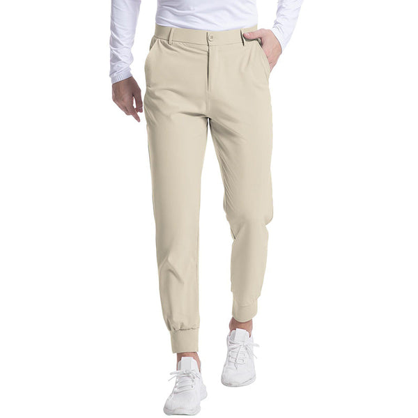 Beige herenbroek met elastische tailleband en zakken, gedragen door model in witte sneakers en shirt. Comfortabele casual stijl.