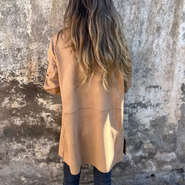 Vrouw in beige jas tegen verweerde muur, casual herfstmode, lange bruine haren, trendy streetwear, stedelijke achtergrond, modefotografie.