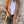 Vrouw in bruine suède jas, witte top en zwarte jeans tegen betonnen muur. Modieuze herfstkleding, casual damesoutfit, trendy jasstijl.