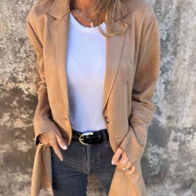 Vrouw in beige blazer, witte top en zwarte jeans tegen een betonnen muur. Modieuze dameskleding, casual outfit, herfststijl.
