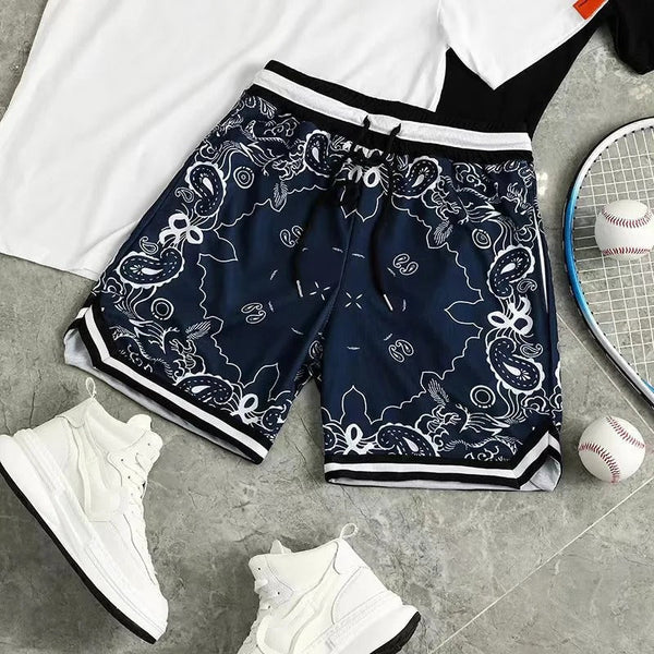 Donkerblauwe sportshort met paisley-patroon, naast witte sneakers, tennisracket en honkbal op grijze vloer. Perfect voor sportieve activiteiten.