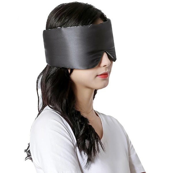 Vrouw draagt zwarte zijden slaapmasker, ideaal voor ontspanning en betere slaap. Comfortabel en stijlvol, perfect voor reizen en thuisgebruik.