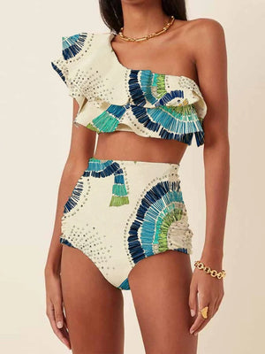 Vrouw in stijlvolle, asymmetrische bikini met kleurrijk patroon, hoge taille en ruches. Perfect voor strandmode en zomerse trends.