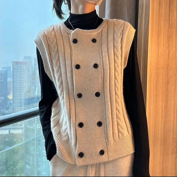 Damesmode: Crèmekleurige kabelgebreide spencer met dubbele rij zwarte knopen, gedragen over een zwarte coltrui. Stijlvol en trendy herfstkleding.
