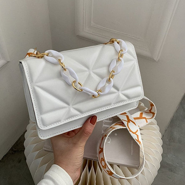 Witte leren handtas met gouden en witte kettingriem, geometrisch patroon, stijlvolle damesmodeaccessoire, luxe design, trendy tas.